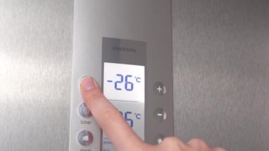 Bir kadının eli buzdolabının düğmelerine basarak sıcaklığı düşürür..