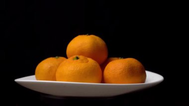 yakın plan mandalinalar bir pikapta dönüyorlar siyah bir arka planda bir tabakta