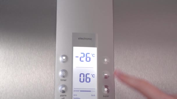 A woman's hand presses buttons in the refrigerator lowering the temperature. — Stock Video