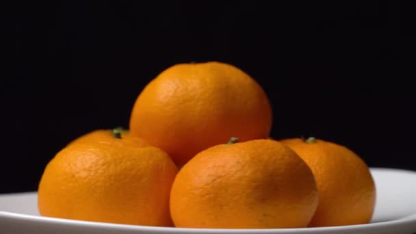 Close-up of tangerines spinning on a turntable on a plate on a black background — Stock Video