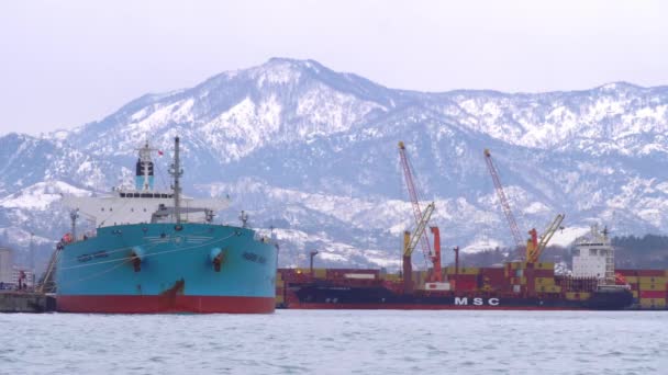 Ferry se encuentra en el puerto contra el telón de fondo de las montañas nevadas. — Vídeos de Stock