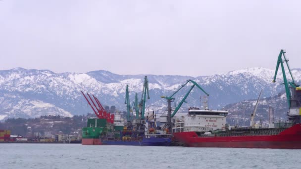 Ferry se encuentra en el puerto contra el telón de fondo de las montañas nevadas. — Vídeos de Stock