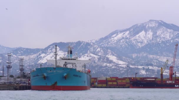 Ferry se encuentra en el puerto contra el telón de fondo de las montañas nevadas. — Vídeos de Stock