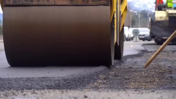 Pavimentadora, o una máquina para la colocación de asfalto nuevo caliente en una calle de la ciudad. — Vídeo de stock