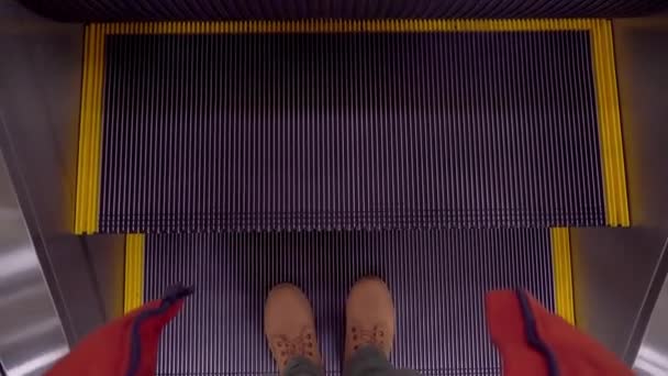 Θέα από ψηλά των ποδιών του ανθρώπου στα παπούτσια του ταξιδιώτη χρησιμοποιώντας μια κινούμενη κυλιόμενη κυλιόμενη σκάλα — Αρχείο Βίντεο