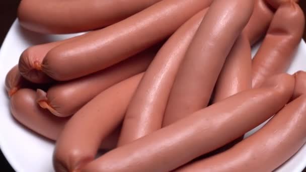 Sausages spinning on a white plate on a black background. — Stock Video