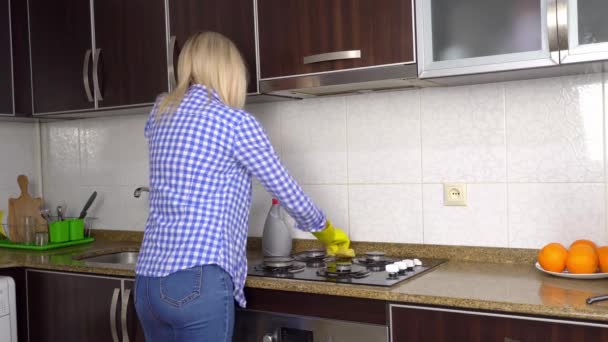 Домогосподарка в жовтих рукавичках миє газову плиту на кухні губкою . — стокове відео