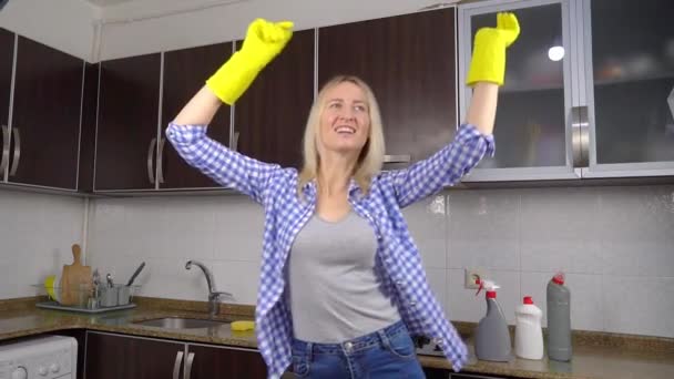 Γυναίκα σε κίτρινο καουτσούκ γάντια καθαρισμού τραγουδά και χορεύει στην κουζίνα — Αρχείο Βίντεο