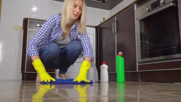 Młoda kobieta w myjniach z bliska kuca lub klęczy na podłodze. — Wideo stockowe