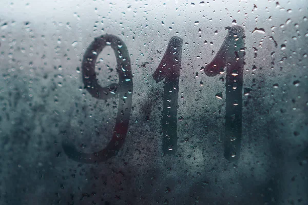 雨の日に濡れた霧ガラスに書かれた911 — ストック写真