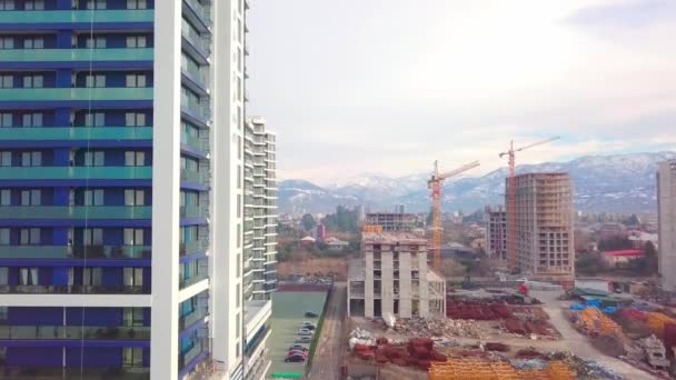 Drönare syn på byggandet av flervåningshus bakgrund berg. — Stockvideo