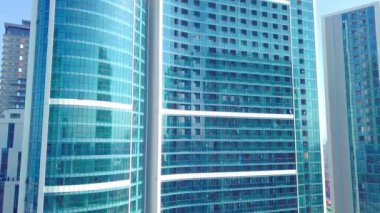 Güneşin, bulutların ve gökyüzünün yansımalarının görüntüsü şehir gökdeleninin cam camlarında.