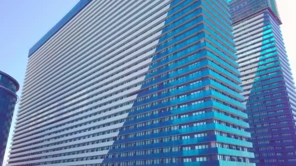 Shot of reflections of sun, clouds and sky on glass windows of city skyscraper. — Stock Video