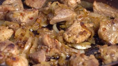 Bir kadının eli kızartma tavasında kızarmış domuz etini çevirir..