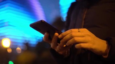 Açık havada cep telefonuyla internette sörf yapan bir kadın..