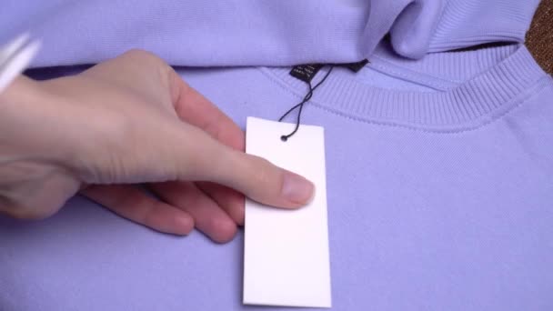 Les mains de la fille avec des ciseaux retirent l'étiquette de prix du pull violet. — Video