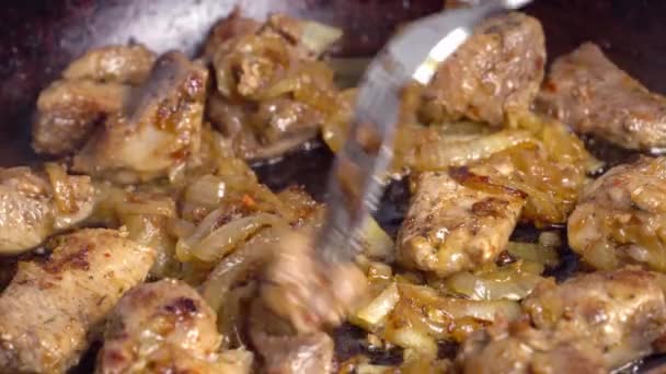 La mano de una mujer da vuelta la carne de cerdo frita en una sartén. — Vídeos de Stock