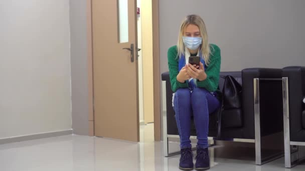 Blondýnka sedí sama na židli v nemocnici s dokumenty — Stock video