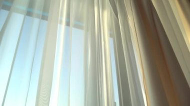 Odadaki açık pencereden rüzgar esiyor. Pencerelerdeki perdeleri sallayan