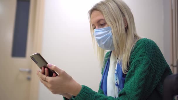 A loira está sentada sozinha em uma cadeira no hospital com documentos — Vídeo de Stock