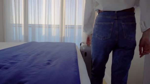 Een jonge vrouw komt de kamer binnen met een koffer, opent een kanten gordijn, — Stockvideo
