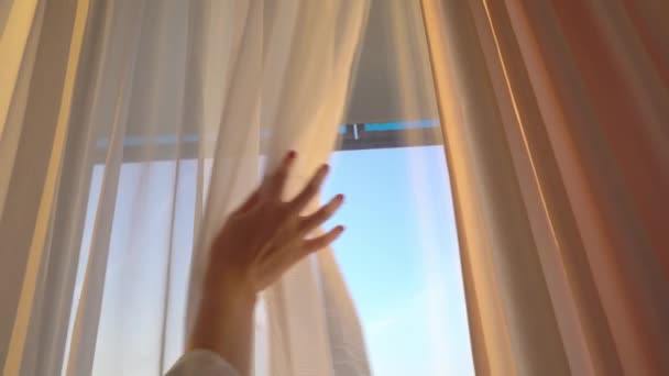 Femme ouvre les rideaux et regarde le lever du soleil, coucher de soleil rayons de soleil tombent sur la silhouette — Video