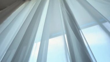 Odadaki açık pencereden rüzgar esiyor. Pencerelerdeki perdeleri sallayan