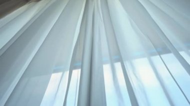 Odadaki açık pencereden rüzgar esiyor. Pencerelerdeki perdeleri sallayan