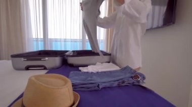 Beyaz gömlekli güzel bir kadın bavulunda bir şeyler topluyor.