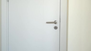 Bir kadının eli, ofiste, dairede ya da otel odasında beyaz ahşap bir kapı açar..