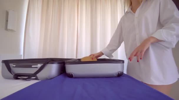 Une jeune belle femme en chemise blanche sort les choses d'une valise — Video