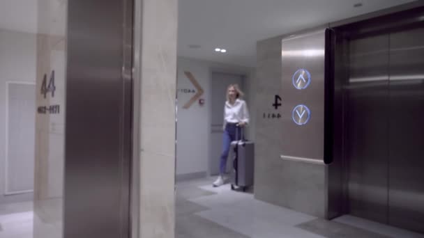 Жінка наближається до дверей ліфта і натискає кнопку виклику ліфта пальцем . — стокове відео