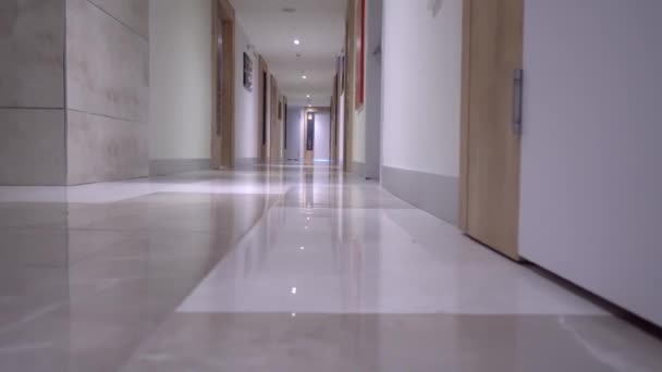 Vista posteriore della donna che cammina lungo il corridoio dell'hotel. rotola il suo bagaglio dietro di lei — Video Stock