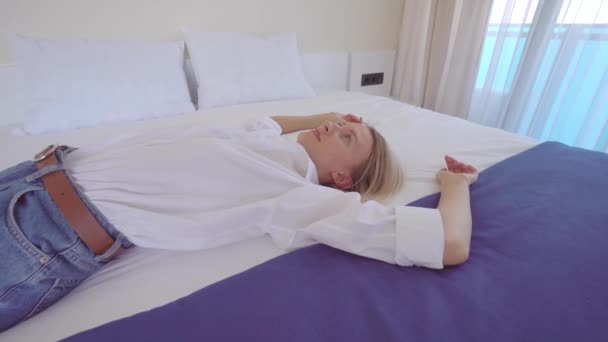 Žena leží na posteli v šatech. Moderní interiér. — Stock video