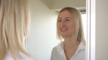 Genç ve güzel bir kadın aynaya bakar ve surat yapar..