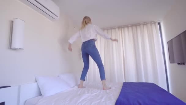 Uma mulher está dançando na cama para a música. — Vídeo de Stock