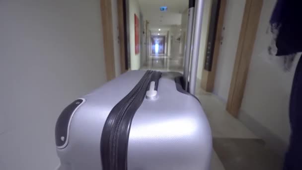 Kvinna går ner korridoren på hotellet och rullar resväska med bagage på hjul. — Stockvideo