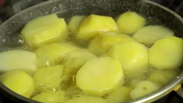 Close-up van kokend water met gele rauwe aardappelen in een pan. — Stockvideo