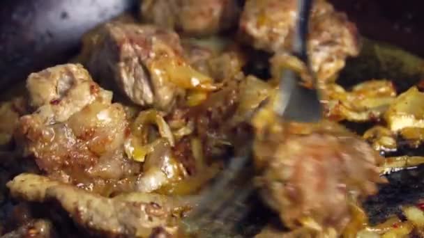 De hand van een vrouw draait gebakken varkensvlees om in een koekenpan. — Stockvideo