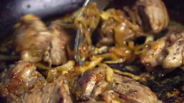 La mano de una mujer da vuelta la carne de cerdo frita en una sartén. — Vídeos de Stock