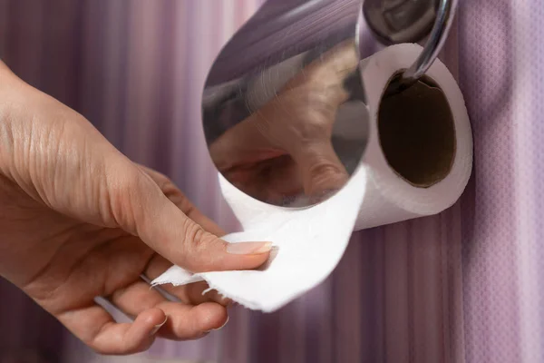 Крупный План Женской Руки Вытаскивающей Туалетную Бумагу Унитаз Сиреневом Фоне — стоковое фото