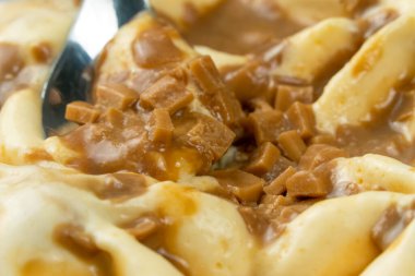 Karamelli dondurmayı tatlı kaşığıyla kepçelemeye yakın çekim. Karamelli dondurmanın makro fotoğrafı.