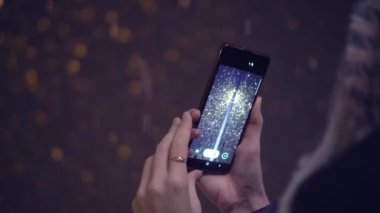Kameraya arkası dönük duran kadın telefonuna kar yağışı yağdırıyor.