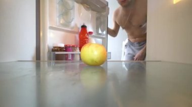 Genç adam buzdolabını açar ve boş raflar görür. Bir elma yalan söylüyor..