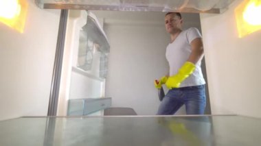 Bir adam yıkamak için buzdolabını açar, gülümseyerek müzik eşliğinde dans eder.