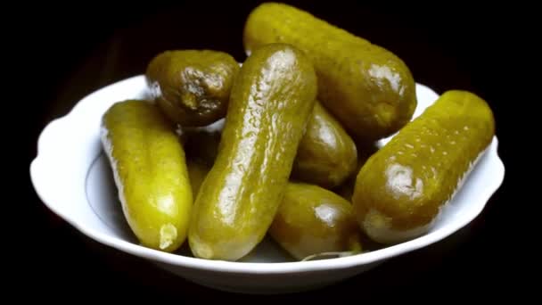 Espinilla pepinos en escabeche primer plano en un plato blanco sobre un fondo negro — Vídeos de Stock