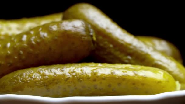 Pimply pickled cucumbers close-up on a white plate on a black background — Stock Video