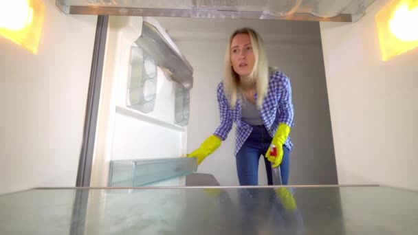 Une femme regarde à l'intérieur du réfrigérateur et crie. Le stress. nettoyage. — Video
