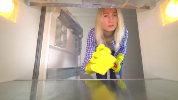 Внутрішній вигляд жінки в гумових рукавичках прибирає порожній холодильник . — стокове відео
