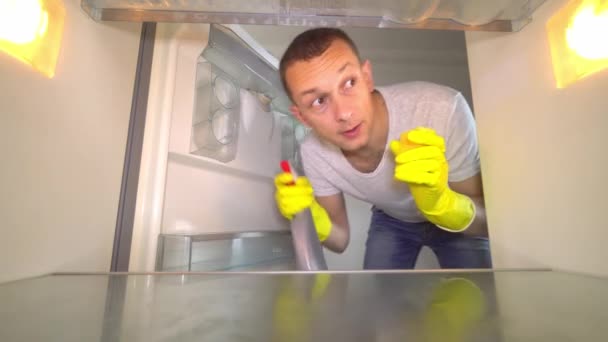 Een man opent de koelkastdeur, kijkt naar binnen, schreeuwt, gek, schoonmaken. — Stockvideo